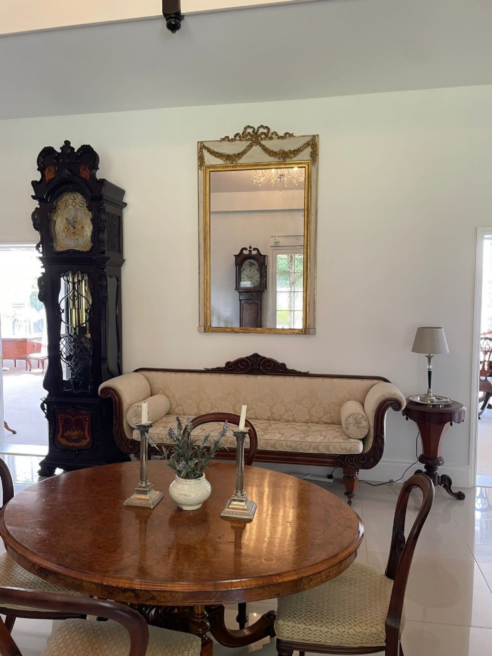 A tall rectangular Victorian mirror featuring a white painted outer frame, gilded beaded inner border, and a gilded ribbon crest with floral swags. View II