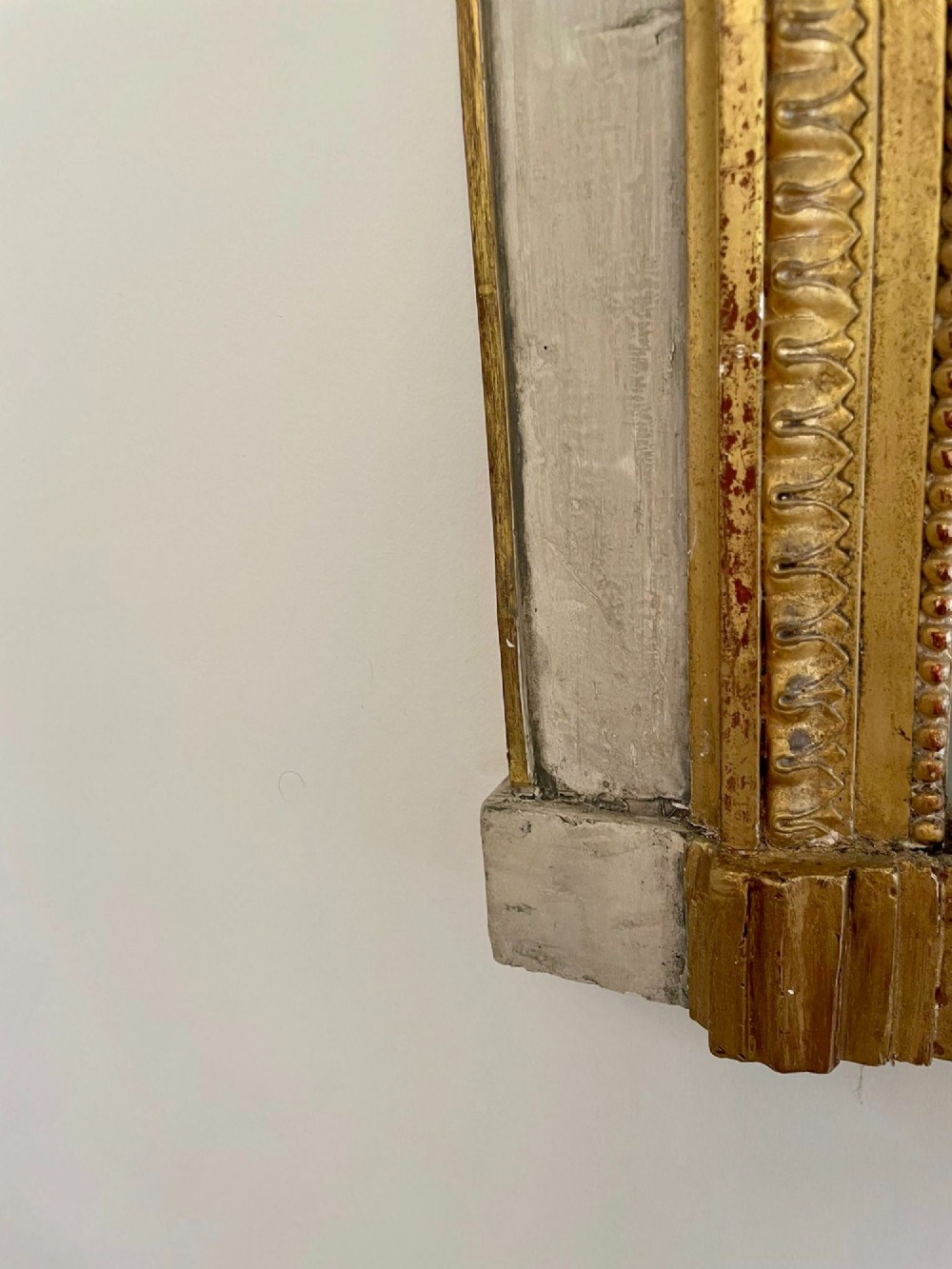 A tall rectangular Victorian mirror featuring a white painted outer frame, gilded beaded inner border, and a gilded ribbon crest with floral swags. View XIV
