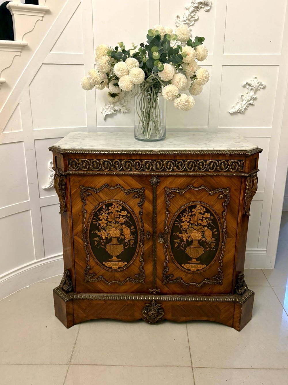 A French Louis XVI style wooden side cabinet featuring a white marble top, gilt-bronze mounts, and two door panels decorated with floral marquetry. View II