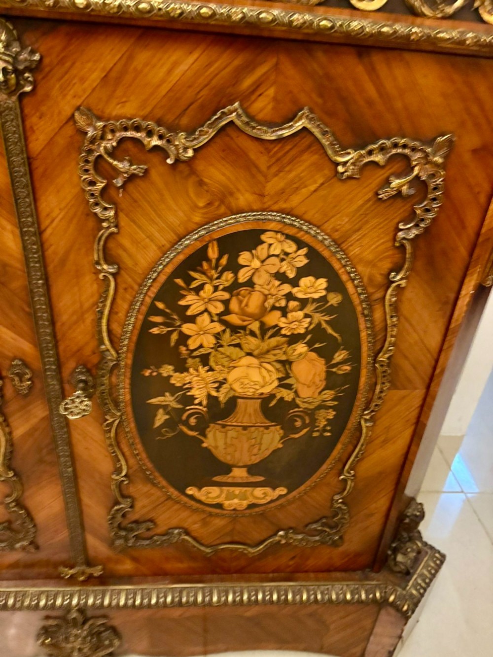 A French Louis XVI style wooden side cabinet featuring a white marble top, gilt-bronze mounts, and two door panels decorated with floral marquetry. View IX