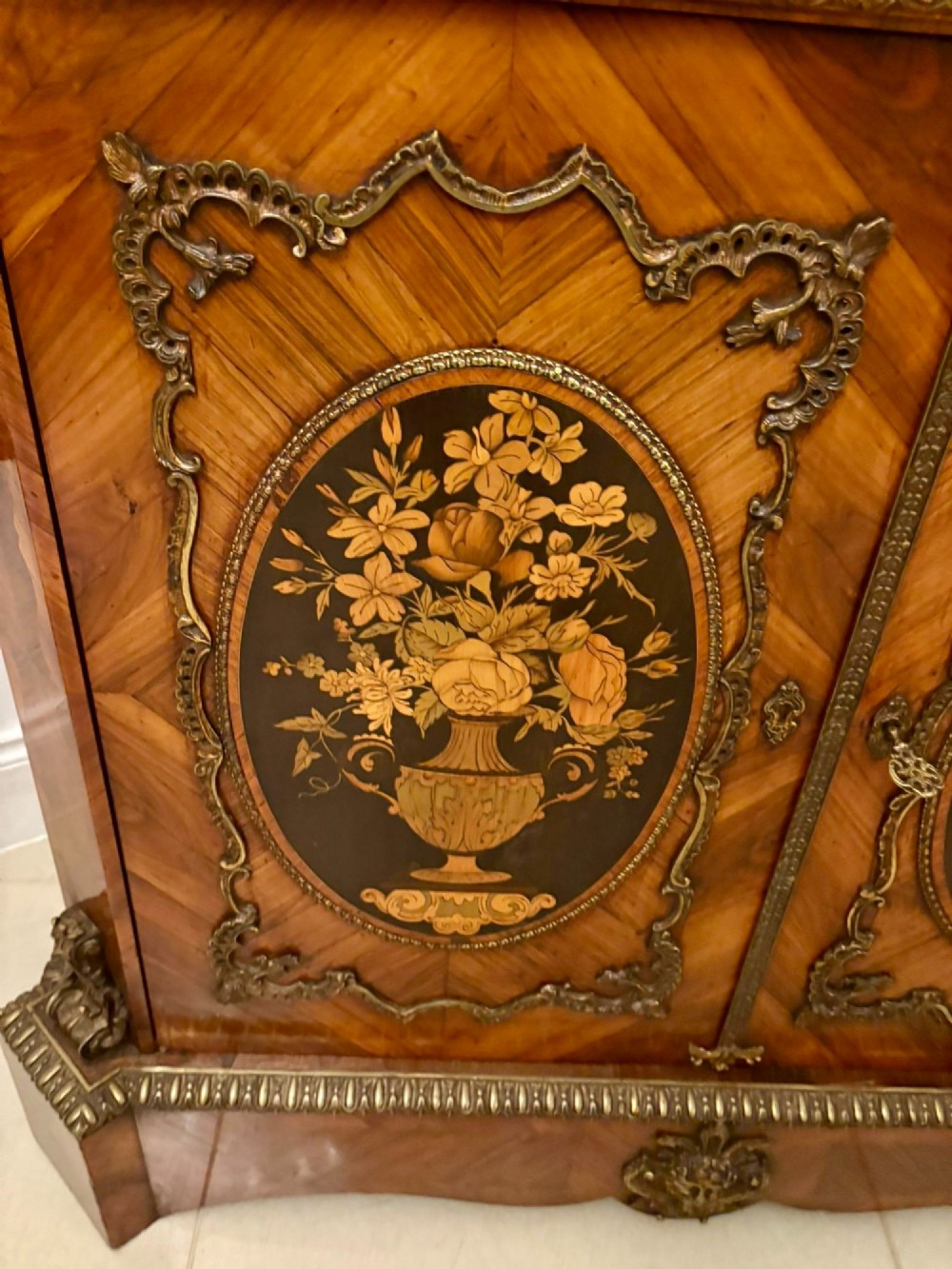 A French Louis XVI style wooden side cabinet featuring a white marble top, gilt-bronze mounts, and two door panels decorated with floral marquetry. View X