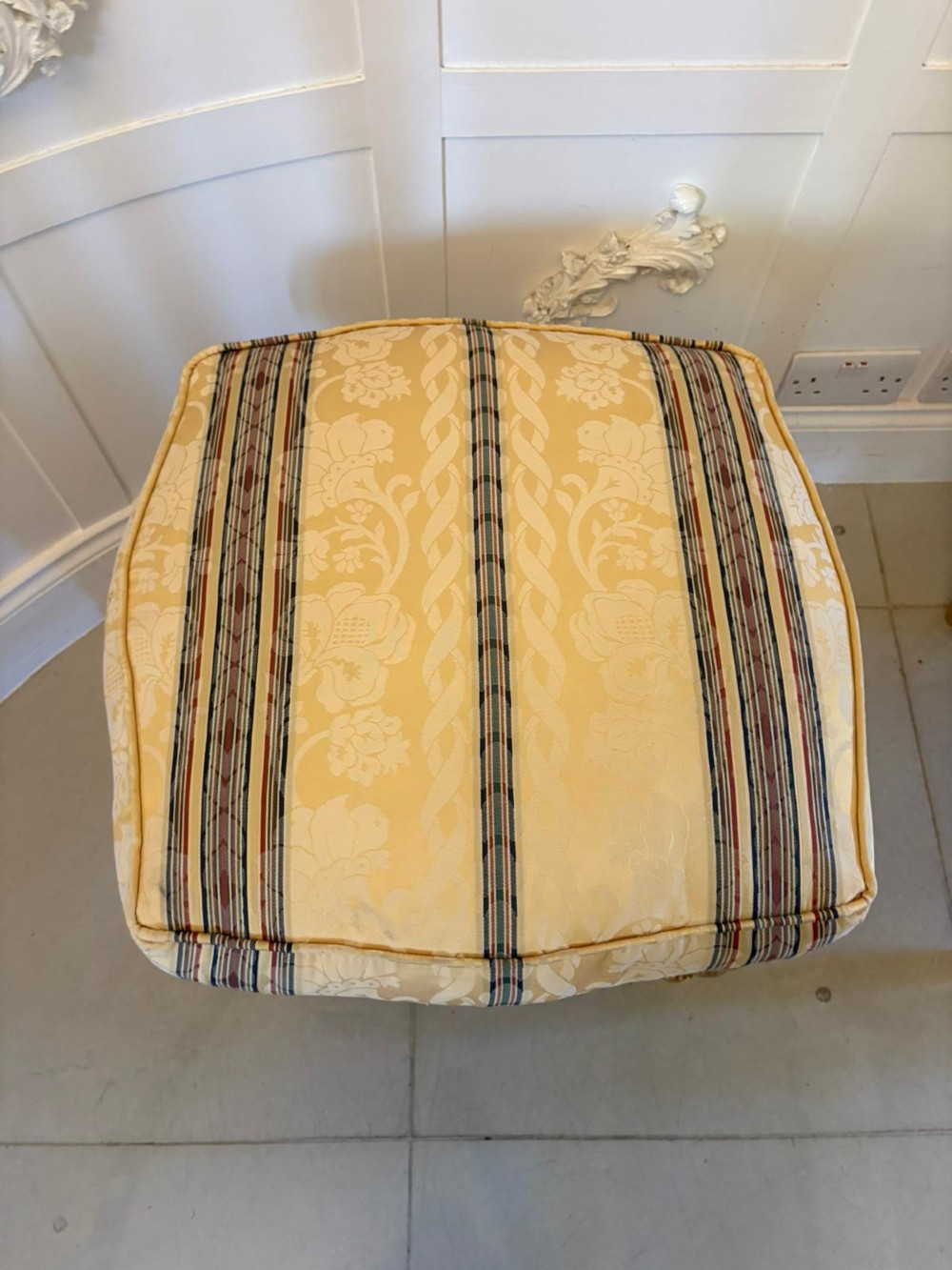 A pair of square French style footstools featuring carved gold giltwood frames, fluted legs, and yellow patterned upholstery. View VI
