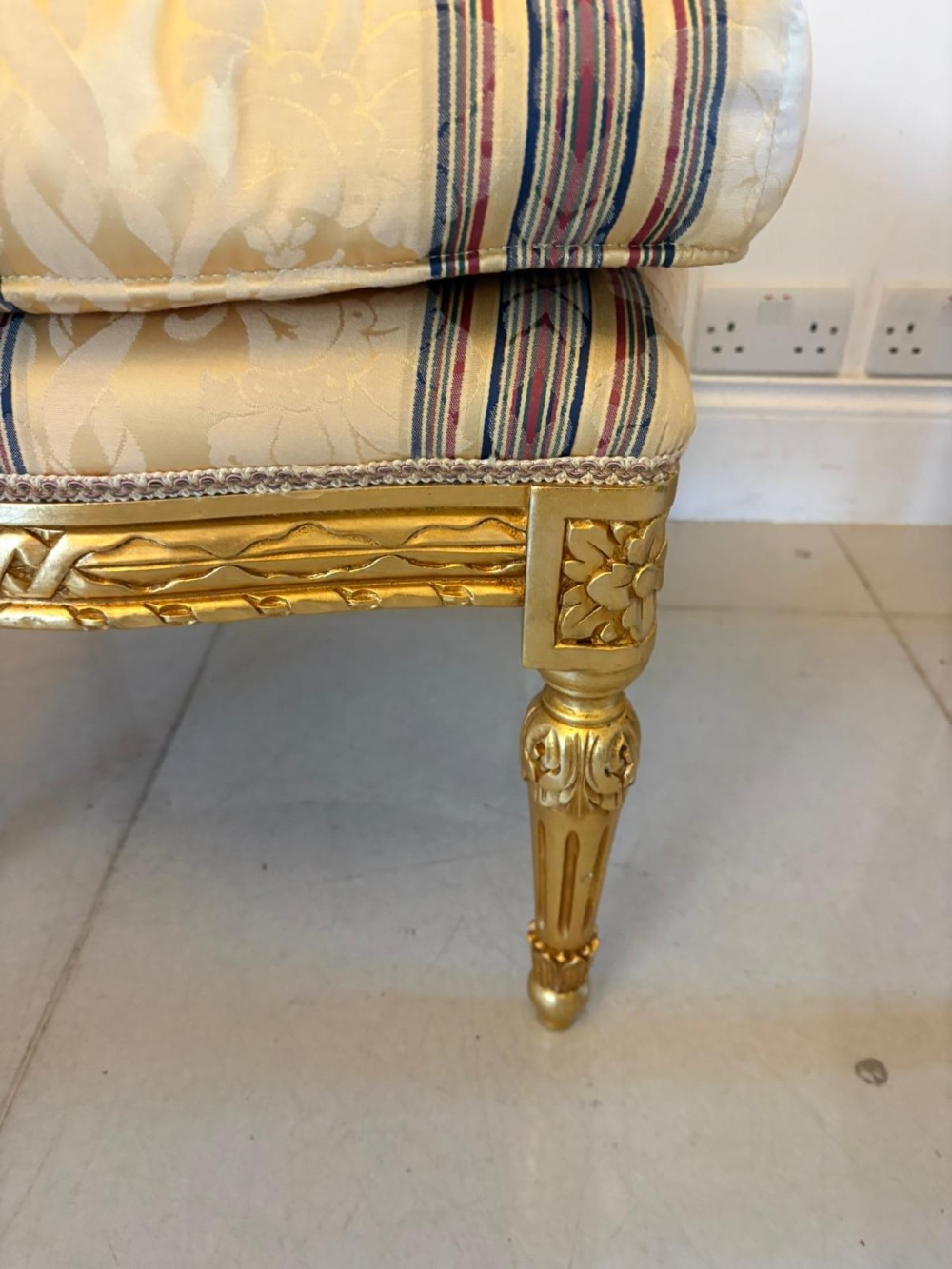 A pair of square French style footstools featuring carved gold giltwood frames, fluted legs, and yellow patterned upholstery. View VII