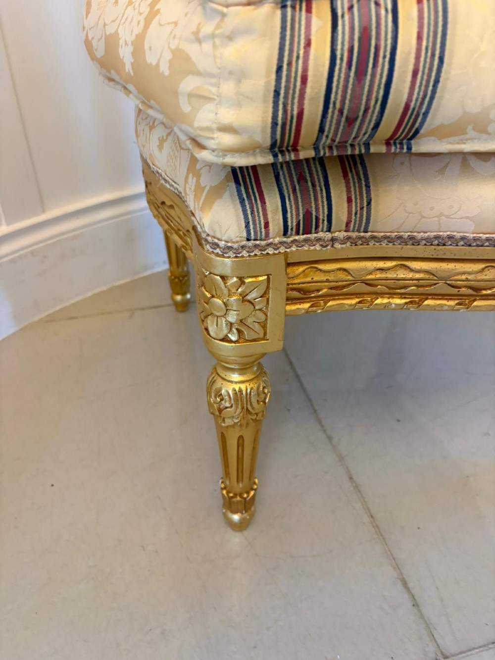 A pair of square French style footstools featuring carved gold giltwood frames, fluted legs, and yellow patterned upholstery. View VIII