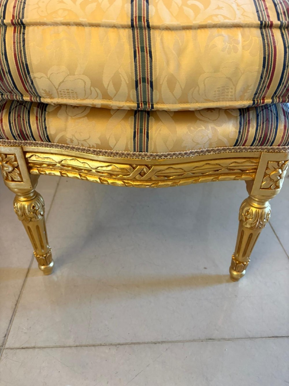 A pair of square French style footstools featuring carved gold giltwood frames, fluted legs, and yellow patterned upholstery. View IX