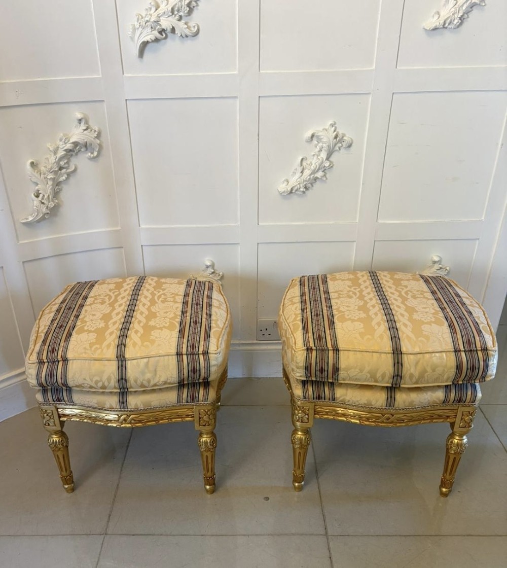 A pair of square French style footstools featuring carved gold giltwood frames, fluted legs, and yellow patterned upholstery. View XII