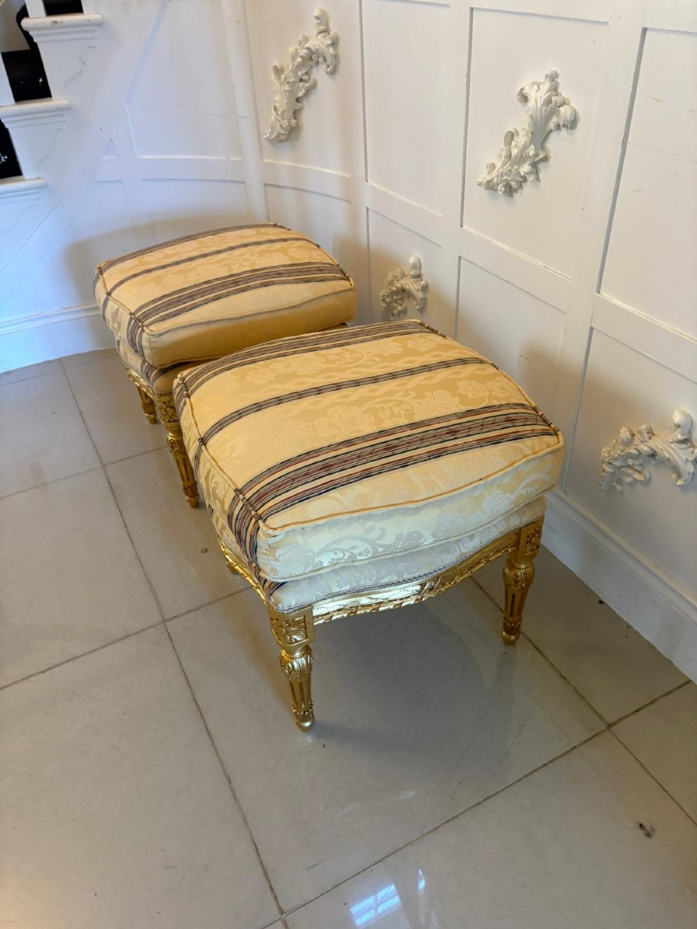 A pair of square French style footstools featuring carved gold giltwood frames, fluted legs, and yellow patterned upholstery. View XIII