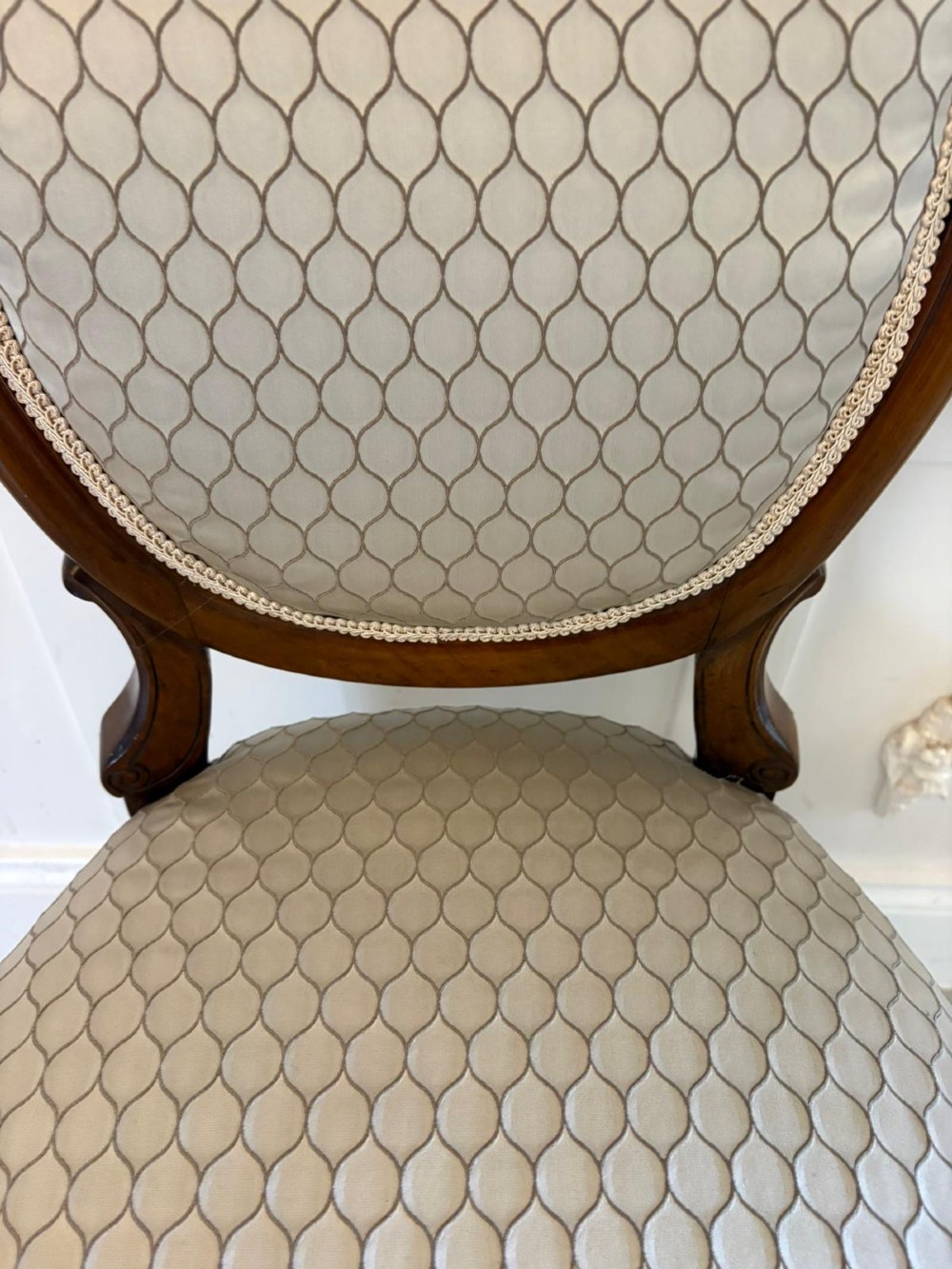 An eleven-piece antique Victorian carved walnut salon suite featuring a central sofa, pair of armchairs, six side chairs, and two footstools, all upholstered in a patterned cream fabric. View VIII