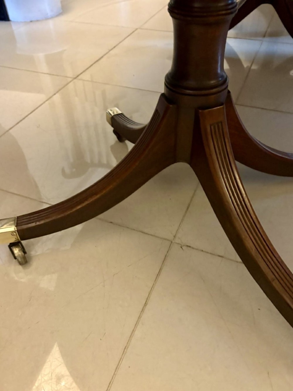 A large mahogany extending dining table featuring an oval surface with two additional leaves, supported by splayed pedestal legs with brass castors. View VII