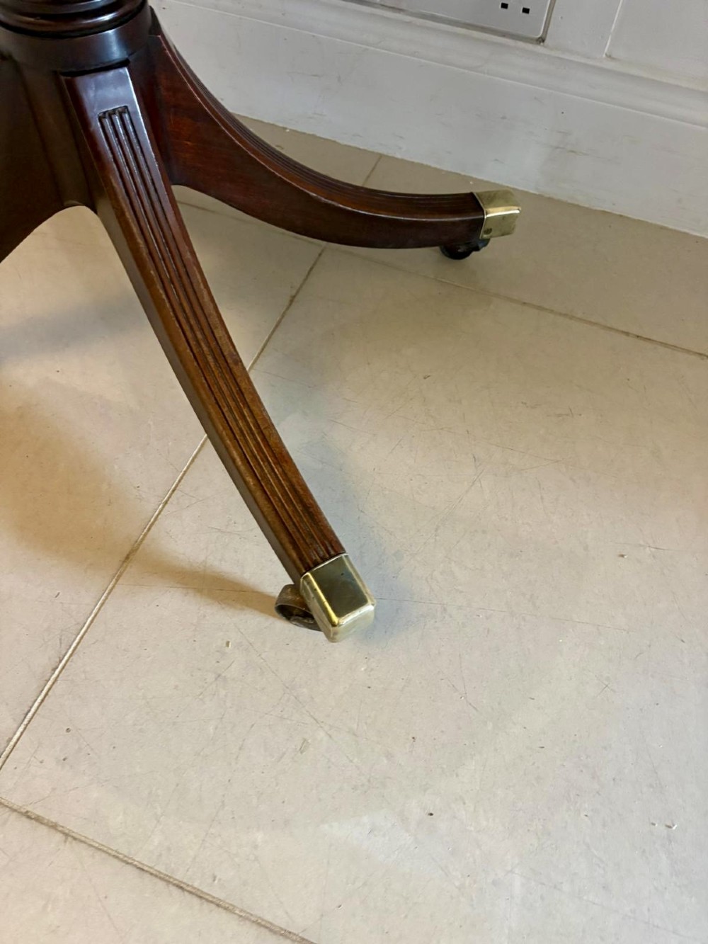 A large mahogany extending dining table featuring an oval surface with two additional leaves, supported by splayed pedestal legs with brass castors. View XIII