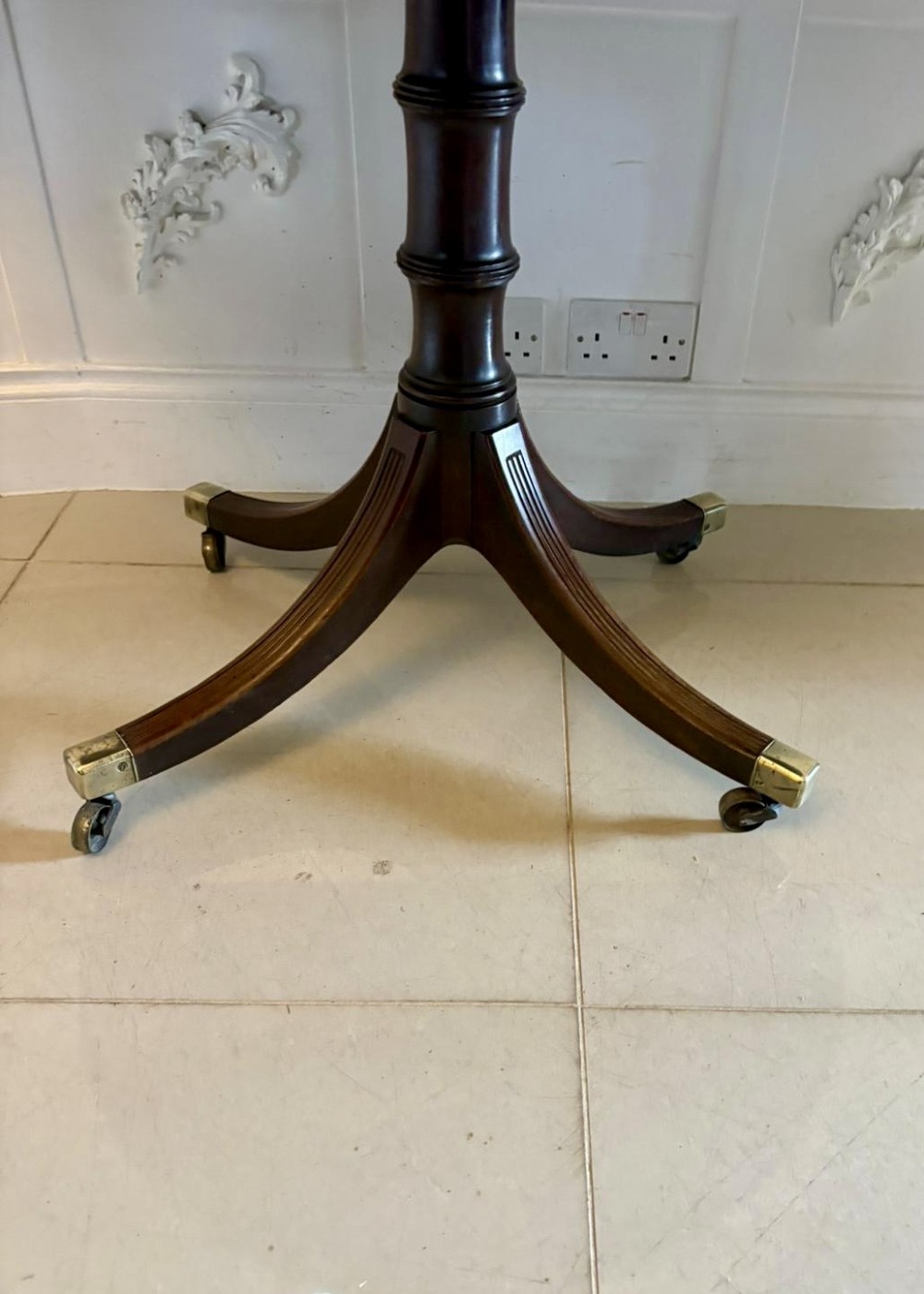 A large mahogany extending dining table featuring an oval surface with two additional leaves, supported by splayed pedestal legs with brass castors. View XIV
