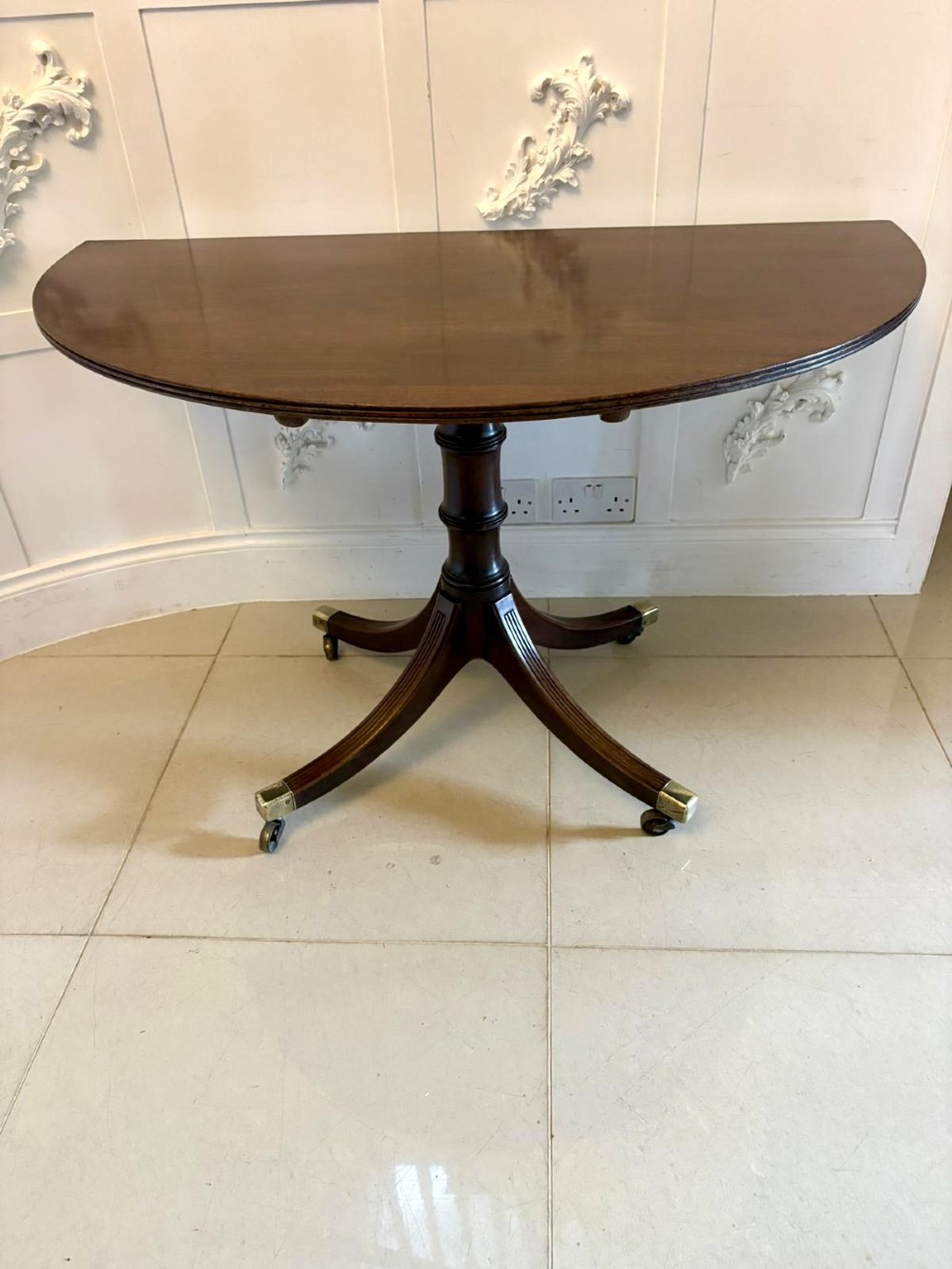 A large mahogany extending dining table featuring an oval surface with two additional leaves, supported by splayed pedestal legs with brass castors. View XV