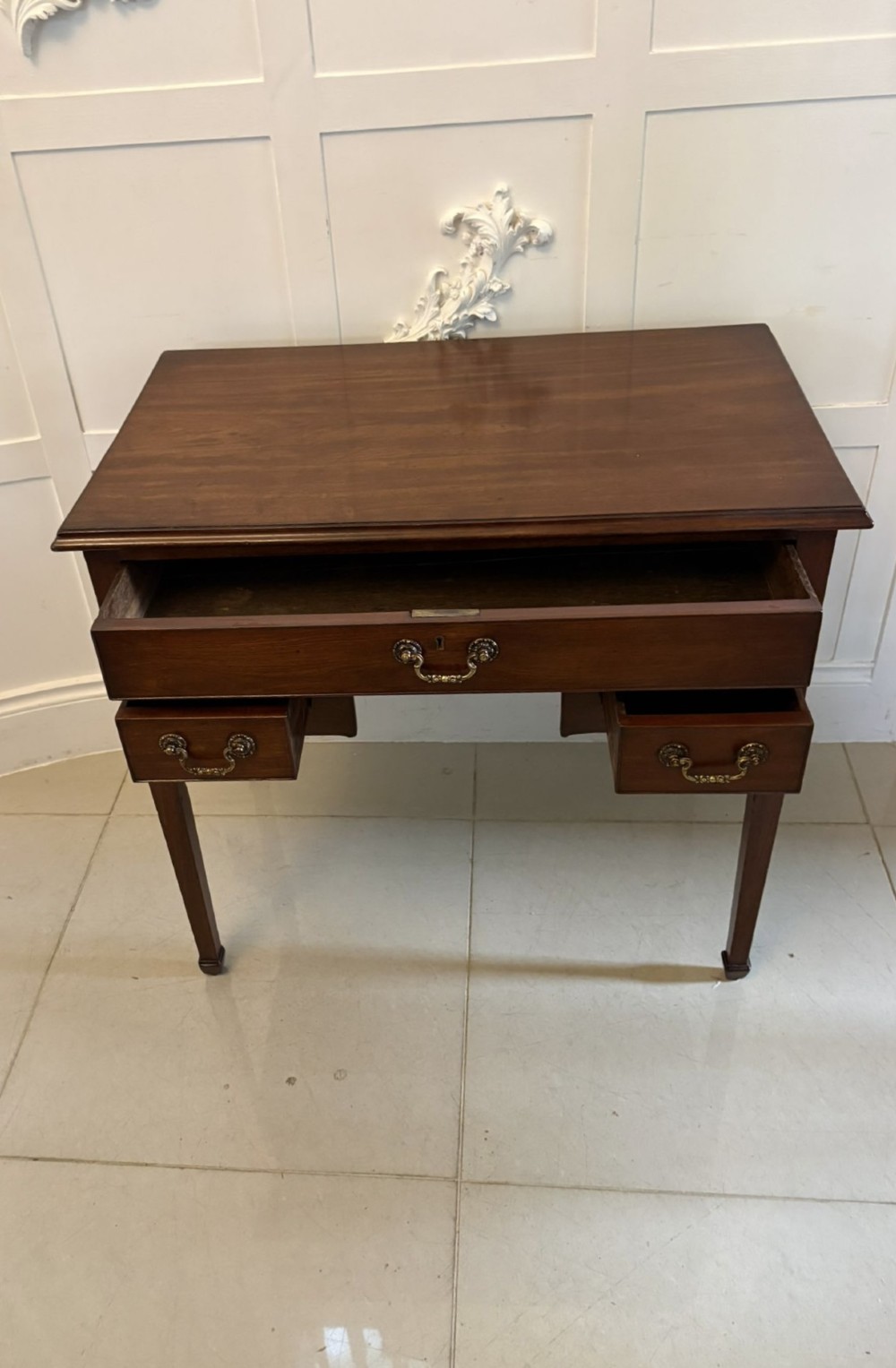 An antique Georgian mahogany lowboy hall table featuring three drawers with brass swan-neck handles and straight square legs. View VII