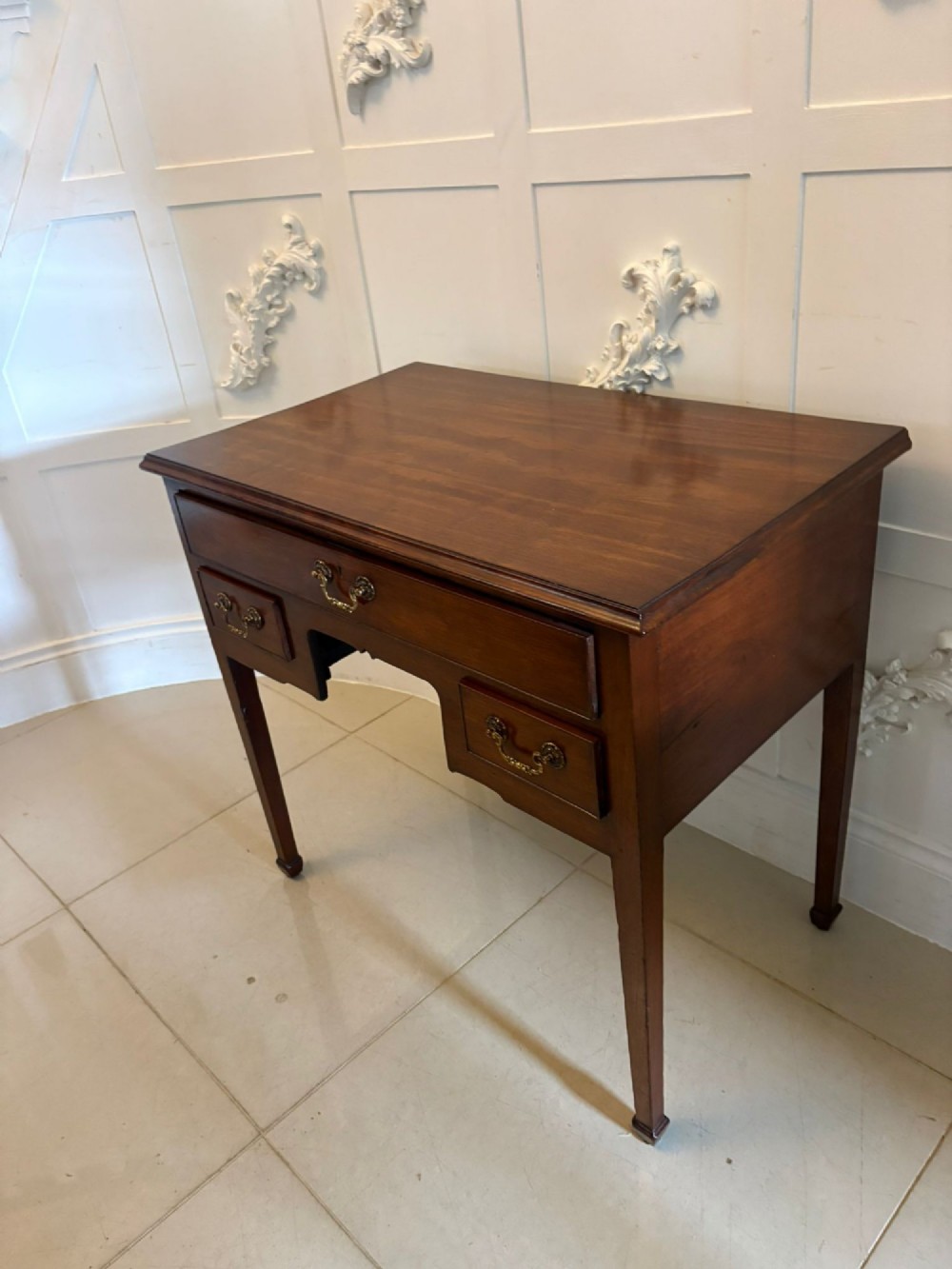 An antique Georgian mahogany lowboy hall table featuring three drawers with brass swan-neck handles and straight square legs. View X