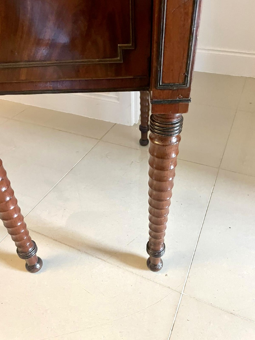 A large George III figured mahogany sideboard featuring a raised stage back, multiple drawers, side cupboards, brass ring handles, and turned reeded legs. View IX