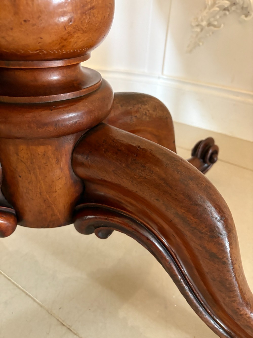 An oval Victorian tilt-top dining table in figured mahogany with satinwood crossbanding, set on a quadruped pedestal base with brass castors. View X