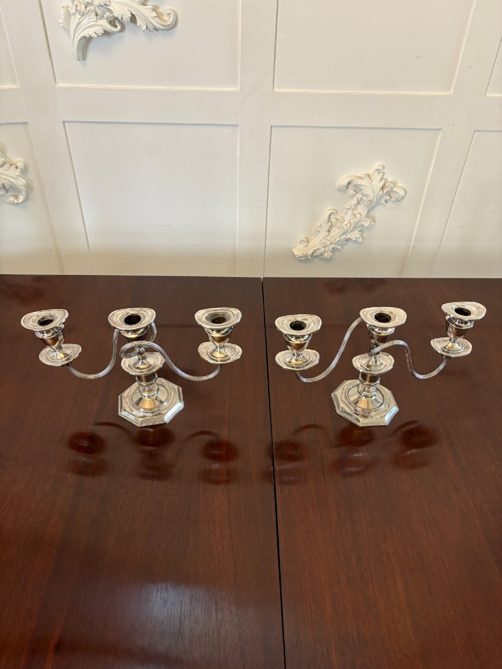 A matching pair of Edwardian silver plated three-light candelabras with octagonal bases and curved reeded arms.