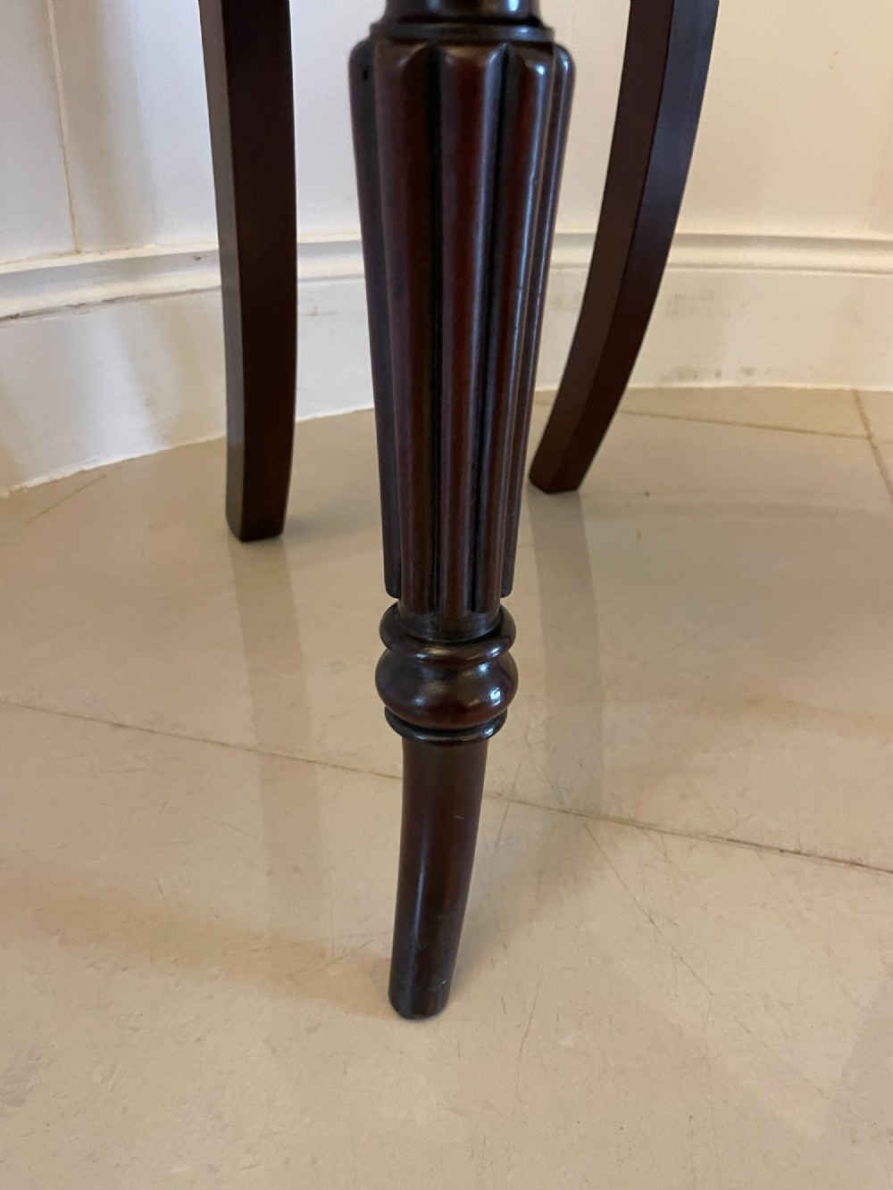 A pair of antique Regency dark mahogany hall chairs featuring scroll-carved cartouche backrests, solid timber seats, and reeded front legs. View VI