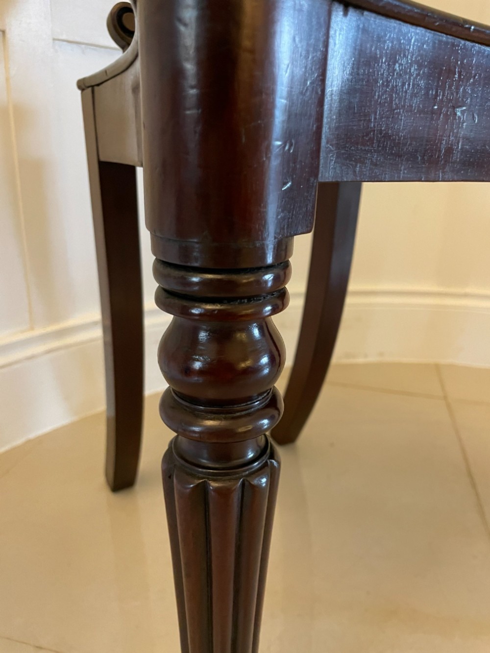 A pair of antique Regency dark mahogany hall chairs featuring scroll-carved cartouche backrests, solid timber seats, and reeded front legs. View VII