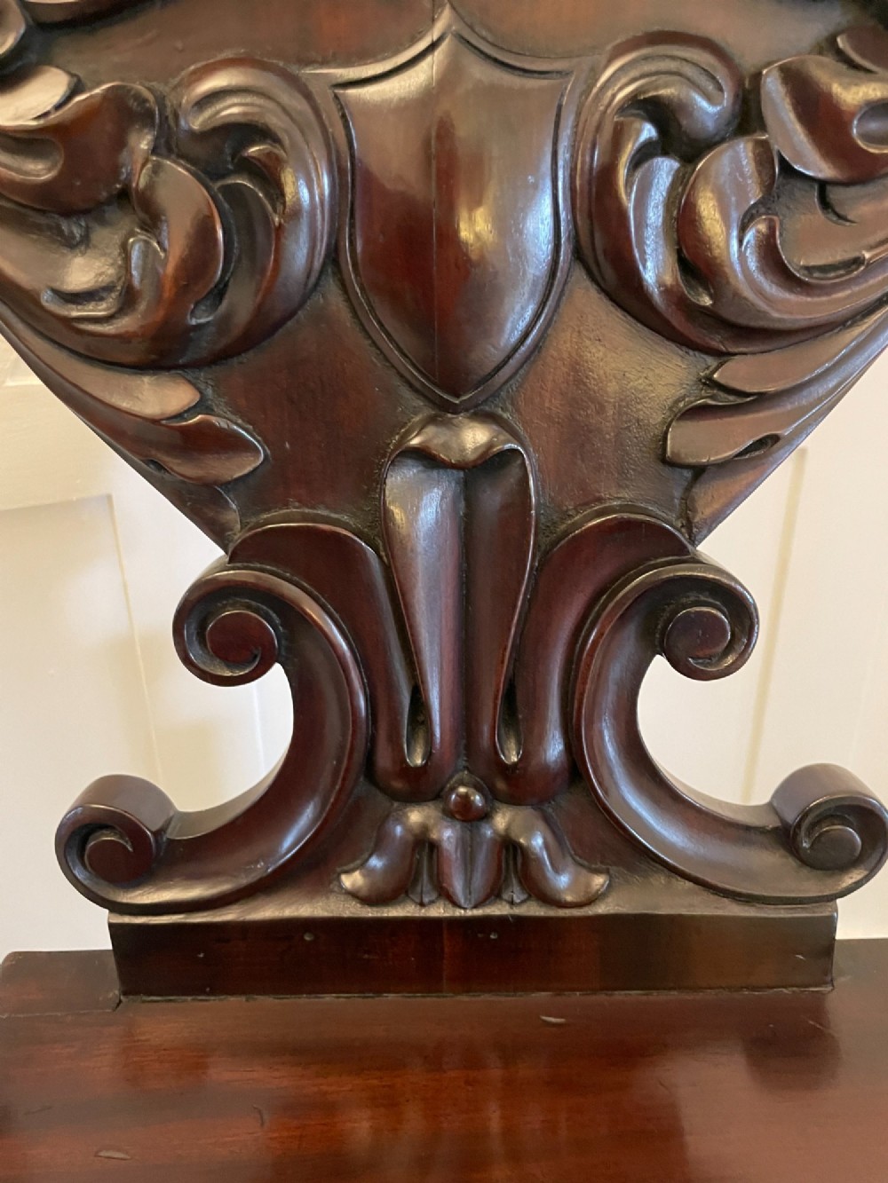 A pair of antique Regency dark mahogany hall chairs featuring scroll-carved cartouche backrests, solid timber seats, and reeded front legs. View VIII