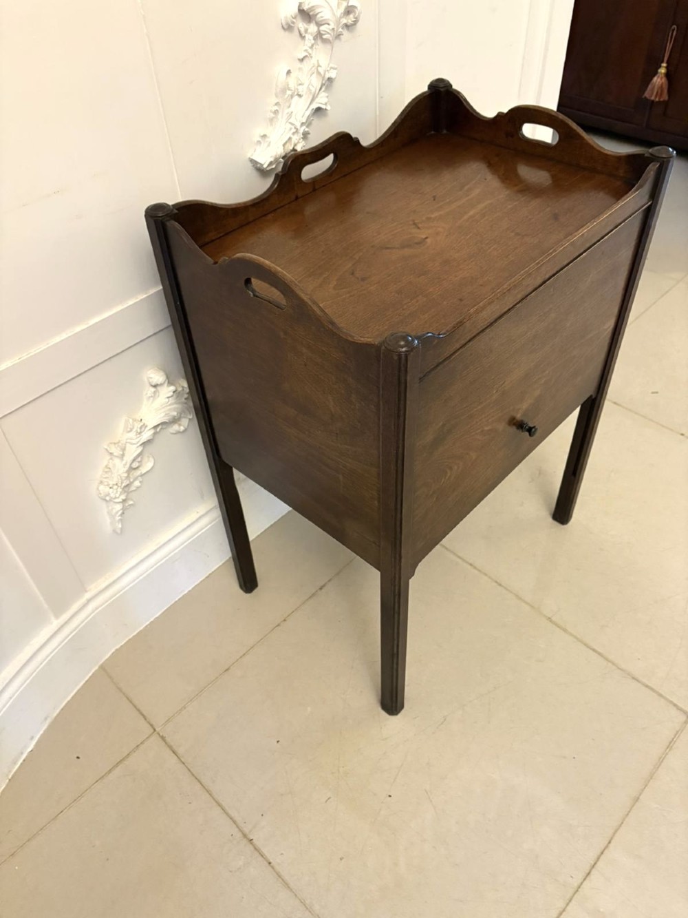 An 18th-century Georgian mahogany bedside cabinet featuring a gallery tray top with cut-out handles, a front cupboard door, and square legs. View IV