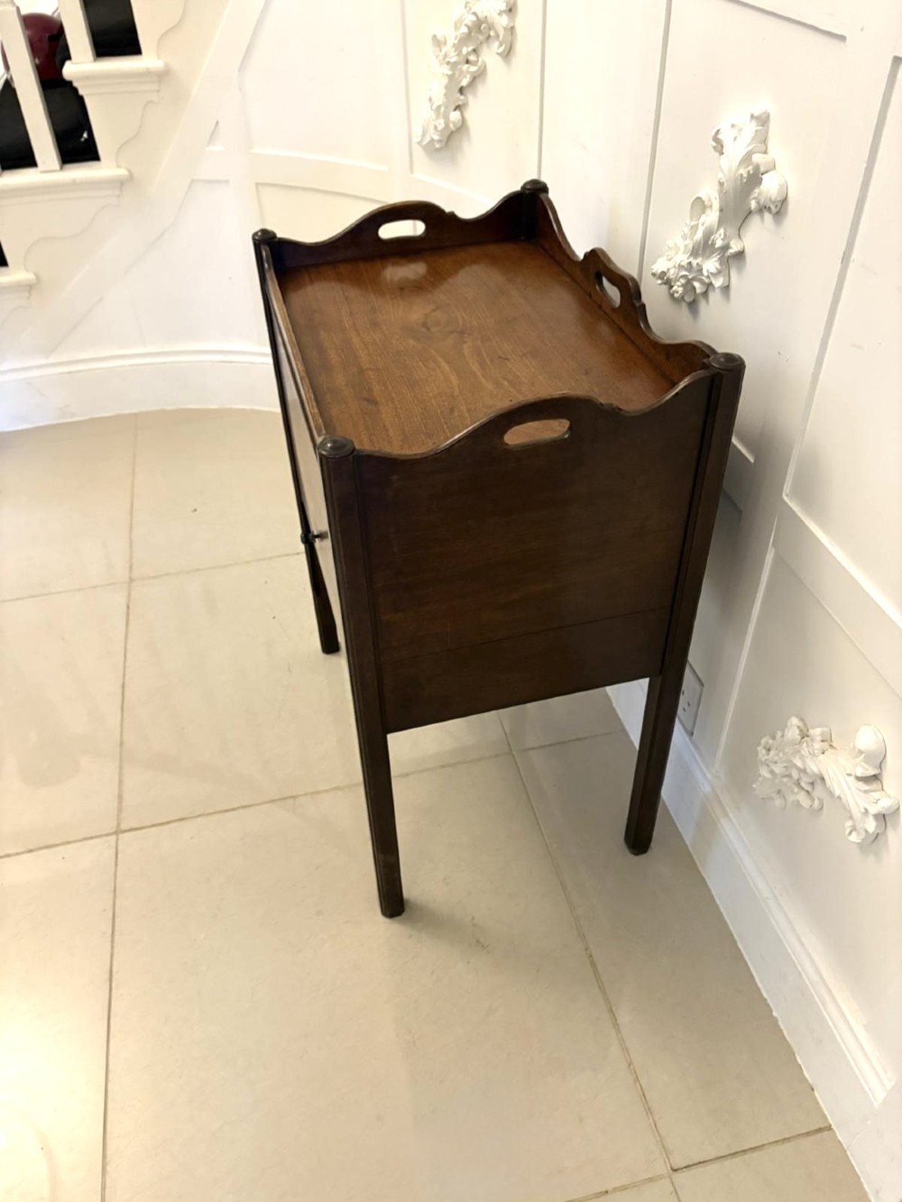 An 18th-century Georgian mahogany bedside cabinet featuring a gallery tray top with cut-out handles, a front cupboard door, and square legs. View VII
