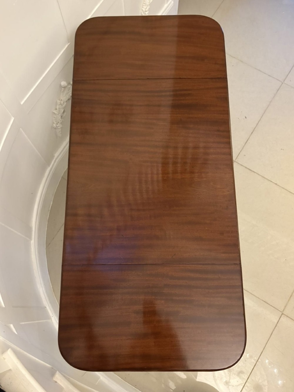 A Regency period mahogany sofa table featuring two drop-leaf sides, a single drawer with brass ring handles, reeded splayed legs, a turned stretcher bar, and brass castors. View VI