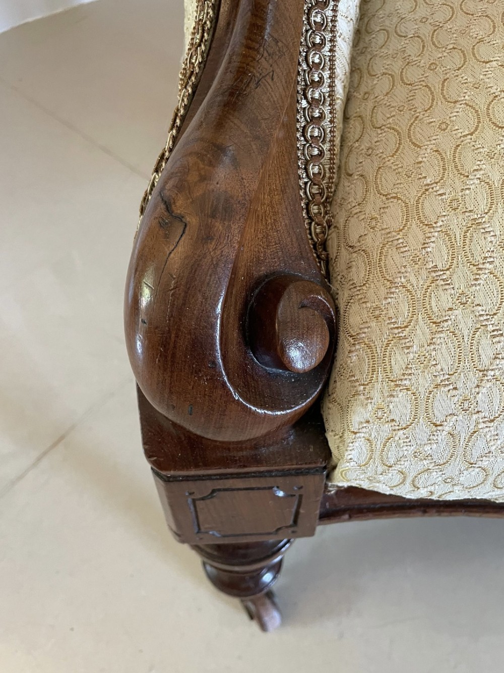 A pair of antique Victorian mahogany armchairs featuring carved show-frames, cream patterned upholstery, and turned front legs on castors. View VII