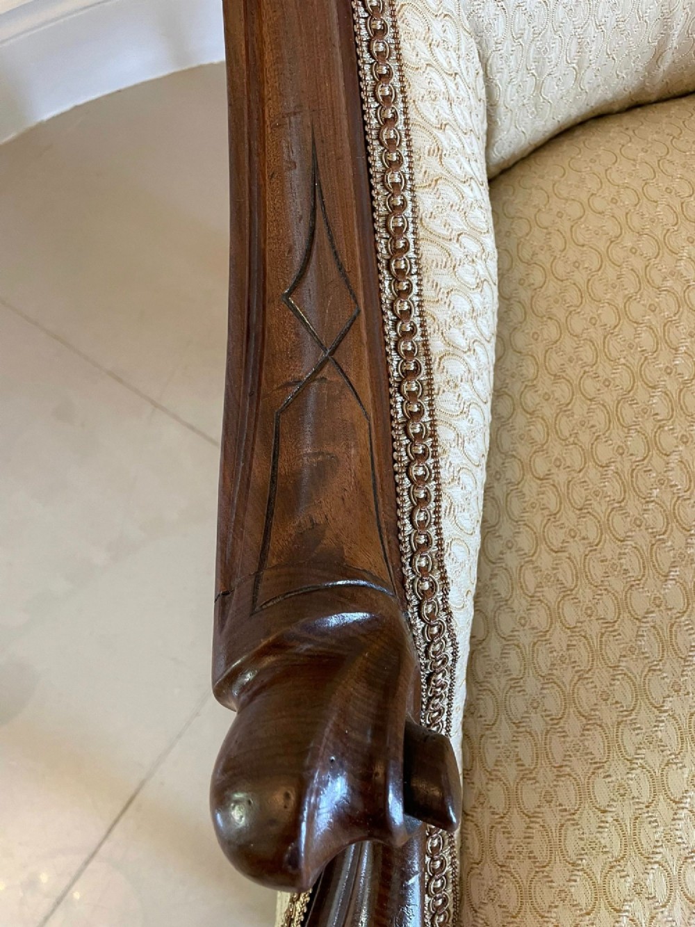 A pair of antique Victorian mahogany armchairs featuring carved show-frames, cream patterned upholstery, and turned front legs on castors. View X