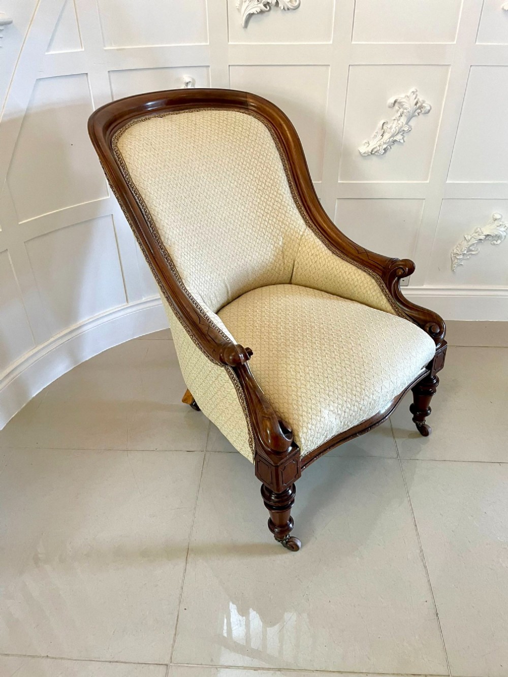 A pair of antique Victorian mahogany armchairs featuring carved show-frames, cream patterned upholstery, and turned front legs on castors. View XI