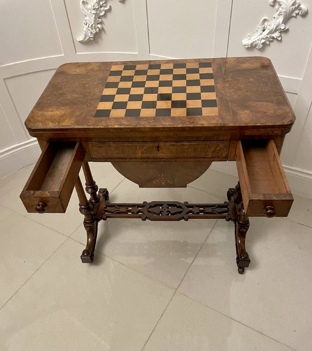 An antique Victorian burr walnut games table featuring an inlaid chessboard top, a frieze drawer, carved turned twin-column supports, and a pierced fretwork stretcher. View III