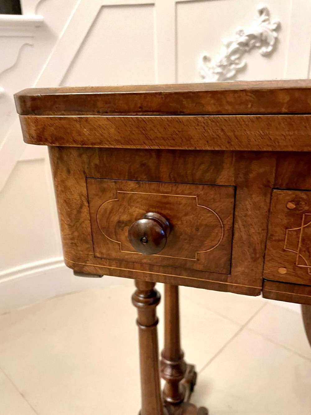 An antique Victorian burr walnut games table featuring an inlaid chessboard top, a frieze drawer, carved turned twin-column supports, and a pierced fretwork stretcher. View V