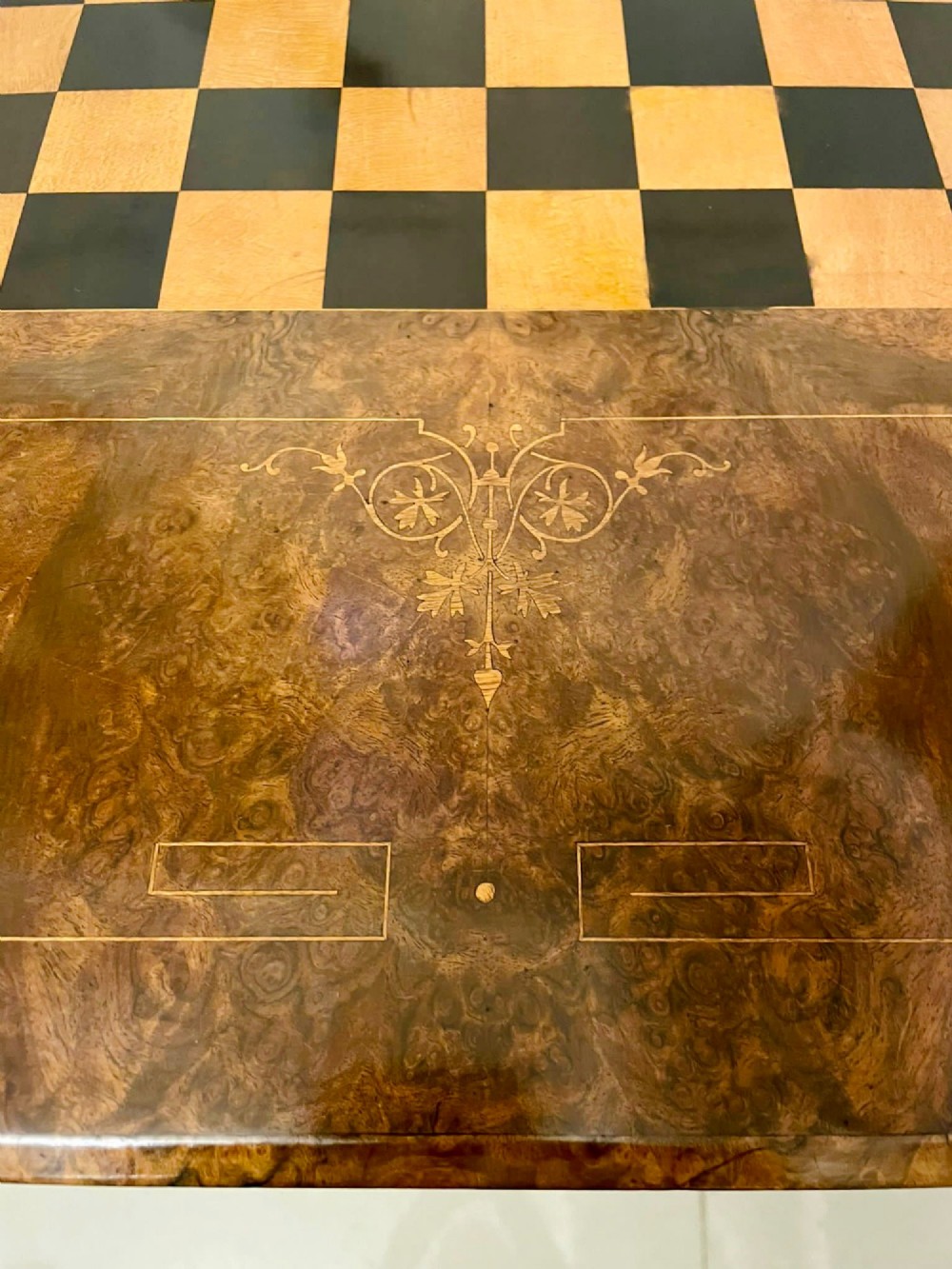 An antique Victorian burr walnut games table featuring an inlaid chessboard top, a frieze drawer, carved turned twin-column supports, and a pierced fretwork stretcher. View X