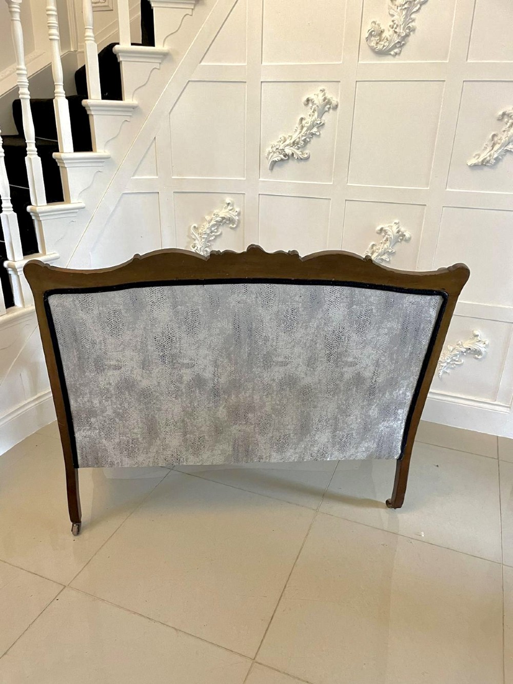 Victorian carved mahogany sofa featuring a decorative crest rail, curved scroll arms, grey textured upholstery, and cabriole legs on brass castors. View III