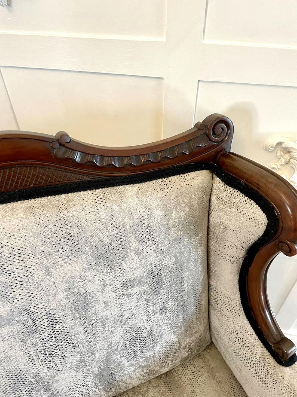 Victorian carved mahogany sofa featuring a decorative crest rail, curved scroll arms, grey textured upholstery, and cabriole legs on brass castors. View VIII