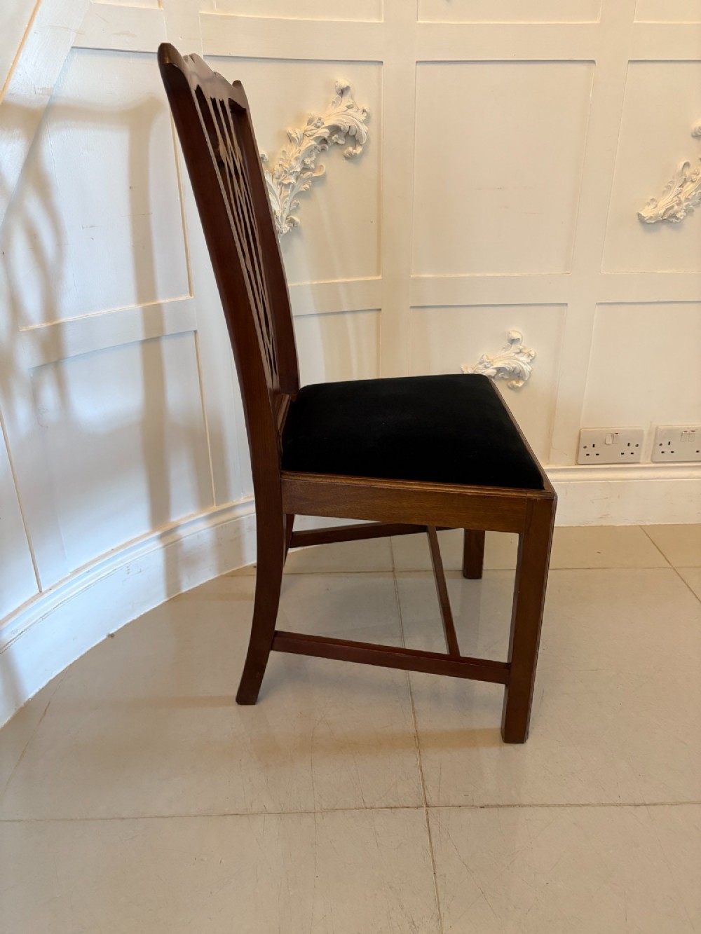 A set of eight Edwardian mahogany dining chairs featuring pierced fretwork splats and black velvet upholstered seats, comprising two carver armchairs and six side chairs. View XI