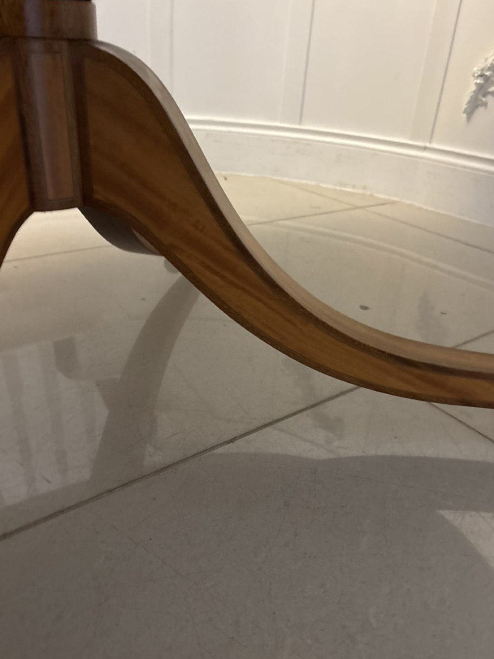An antique Regency style oval mahogany tilt-top dining table featuring a figured timber top with satinwood crossbanding mounted on a pedestal base with brass castors. View III