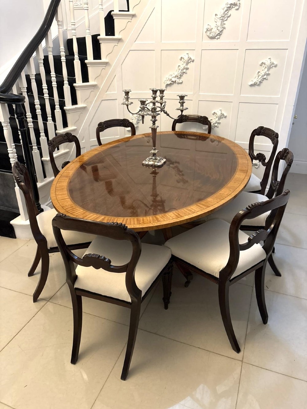 An antique Regency style oval mahogany tilt-top dining table featuring a figured timber top with satinwood crossbanding mounted on a pedestal base with brass castors. View VII