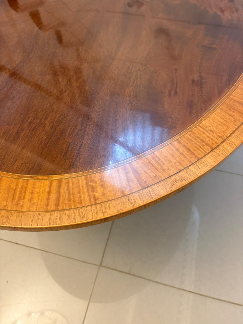 An antique Regency style oval mahogany tilt-top dining table featuring a figured timber top with satinwood crossbanding mounted on a pedestal base with brass castors. View IX