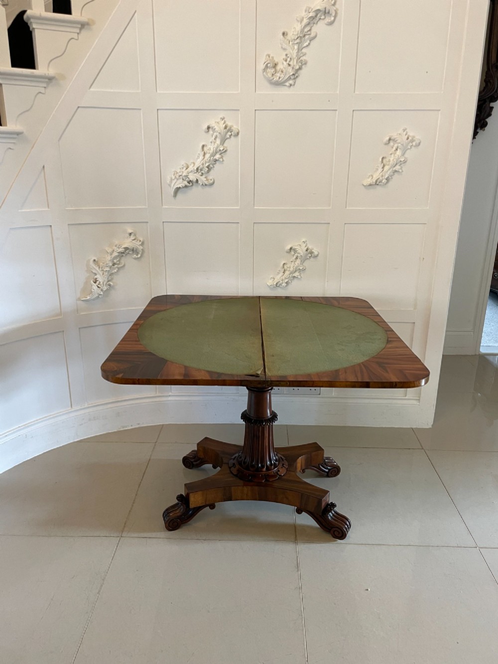An antique Victorian rosewood fold-over card table featuring a carved frieze, a fluted pedestal column, and a quadform base with scroll feet. View III