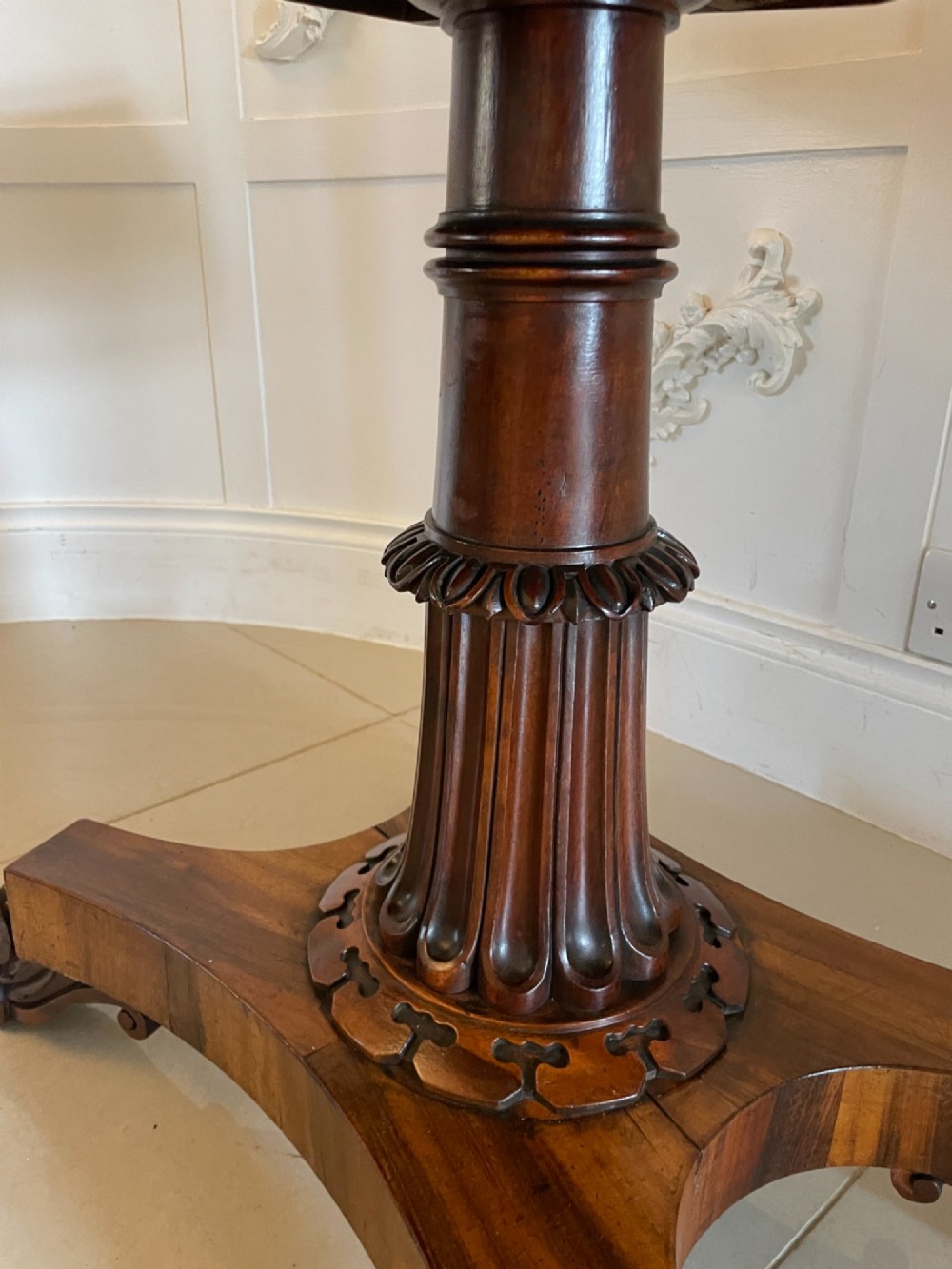 An antique Victorian rosewood fold-over card table featuring a carved frieze, a fluted pedestal column, and a quadform base with scroll feet. View IX