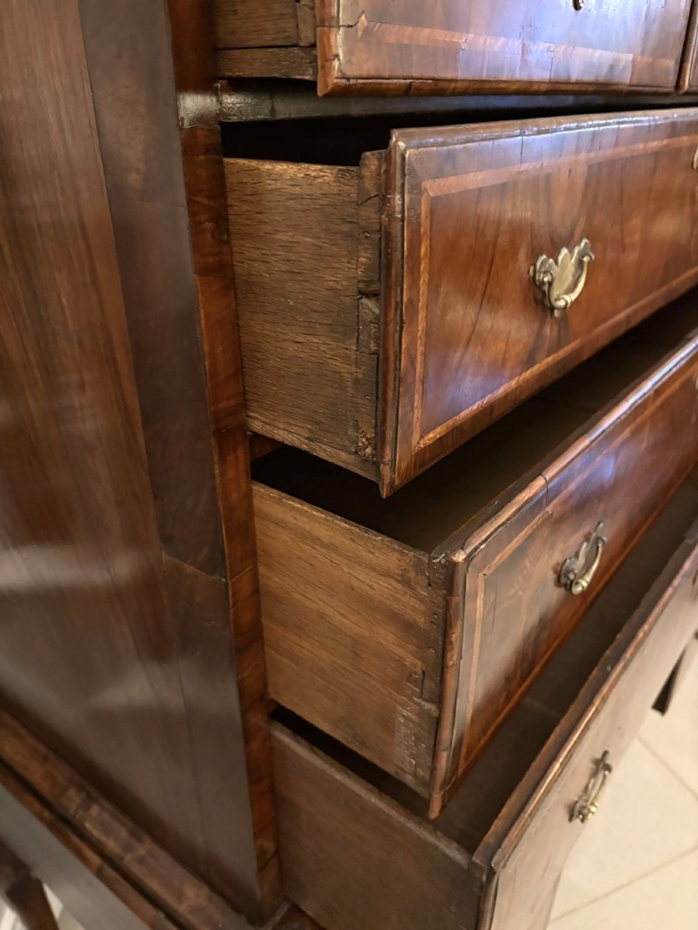 An early eighteenth-century George I walnut chest on stand featuring crossbanded drawers, brass drop handles, and cabriole legs with pad feet. View VIII