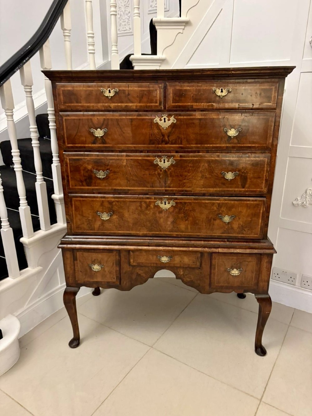 An early eighteenth-century George I walnut chest on stand featuring crossbanded drawers, brass drop handles, and cabriole legs with pad feet. View IX