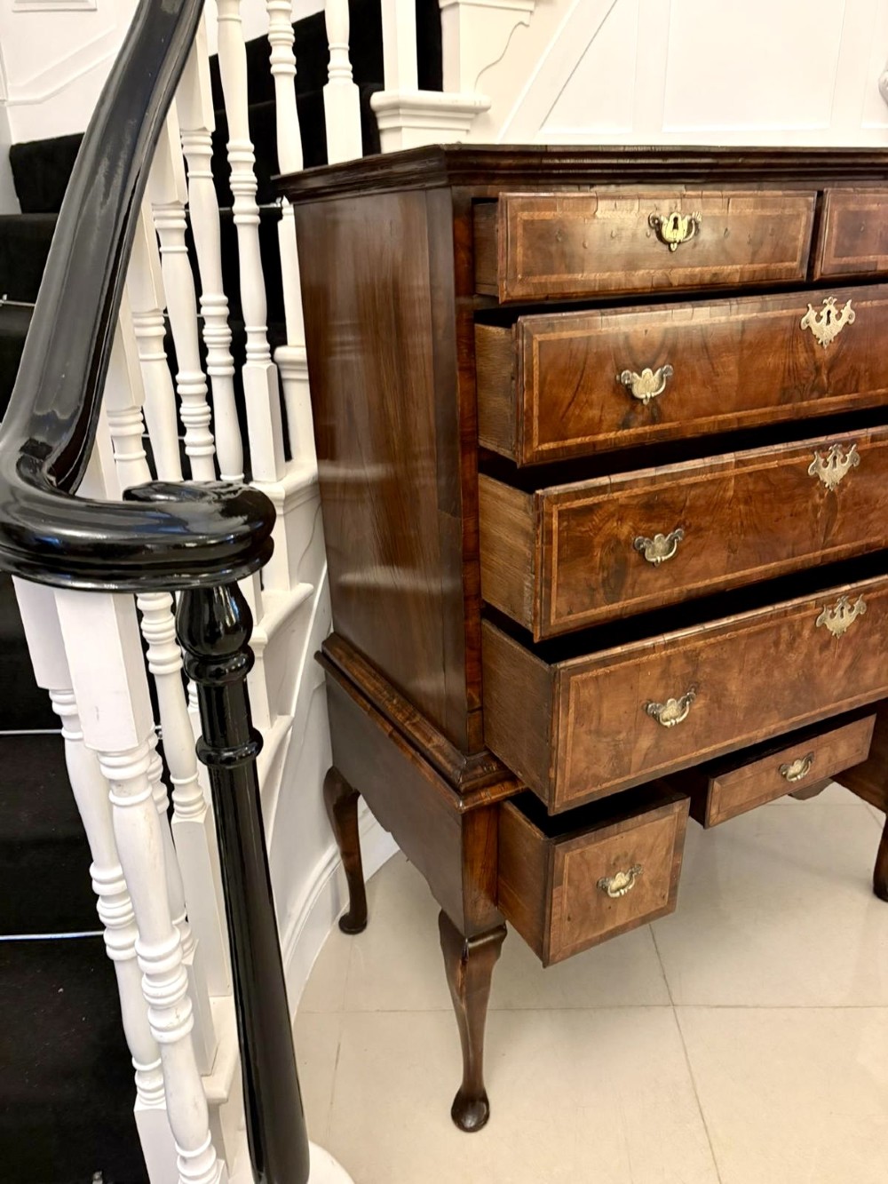 An early eighteenth-century George I walnut chest on stand featuring crossbanded drawers, brass drop handles, and cabriole legs with pad feet. View X