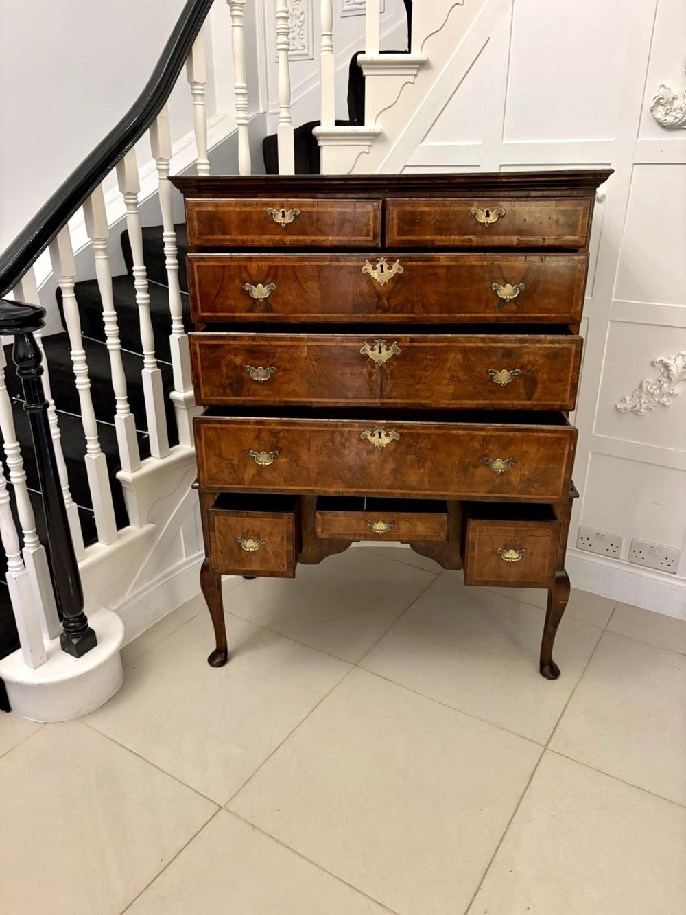 An early eighteenth-century George I walnut chest on stand featuring crossbanded drawers, brass drop handles, and cabriole legs with pad feet. View XI