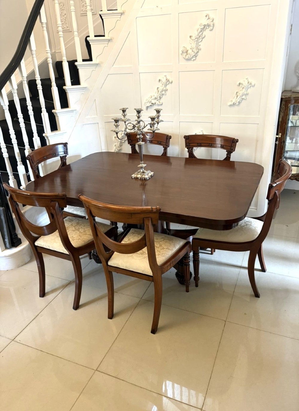 A William IV figured mahogany tilt top dining table shown upright, featuring rounded corners, a smooth grain finish, and a central pedestal base with carved feet. View II