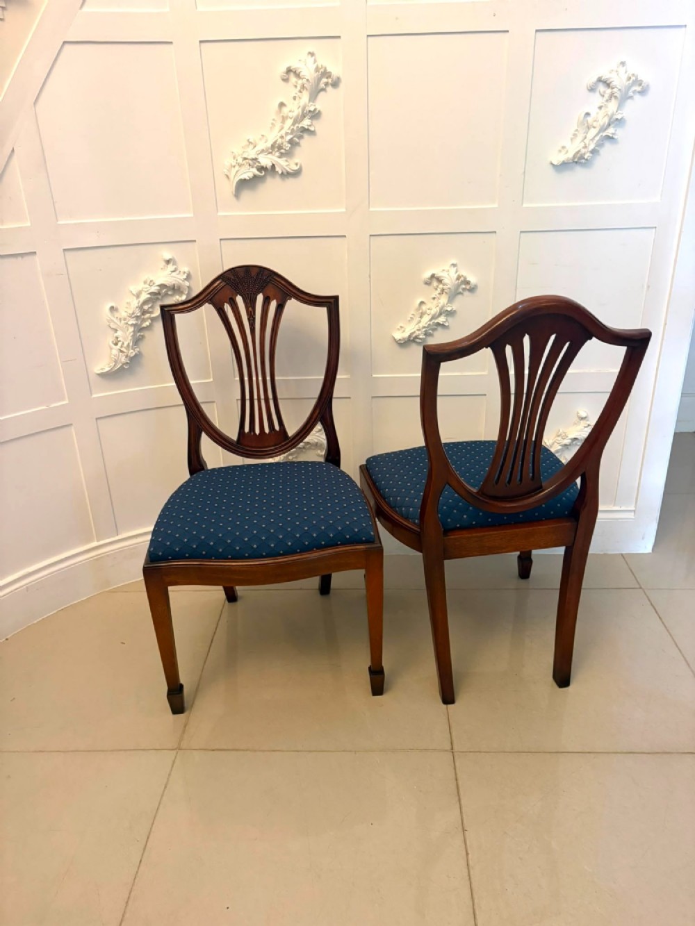 A set of twelve mahogany shield back dining chairs featuring carved backrest splats, square tapered legs, and blue patterned upholstered seats. View III
