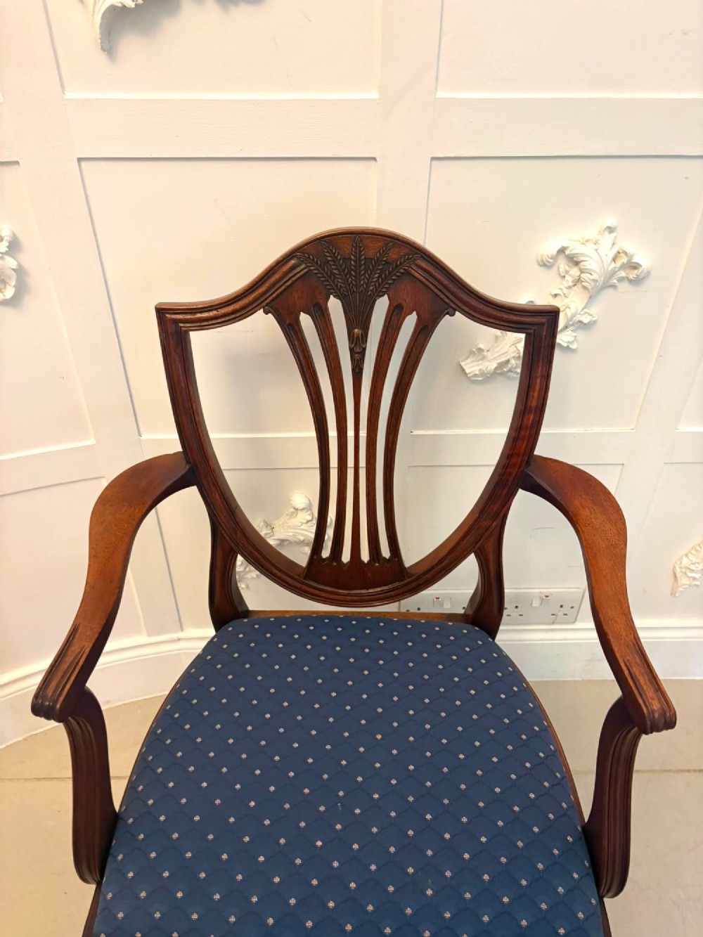 A set of twelve mahogany shield back dining chairs featuring carved backrest splats, square tapered legs, and blue patterned upholstered seats. View IV