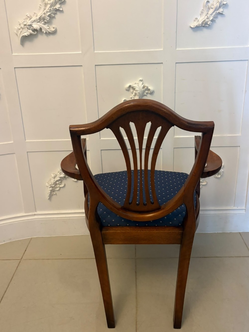 A set of twelve mahogany shield back dining chairs featuring carved backrest splats, square tapered legs, and blue patterned upholstered seats. View VI