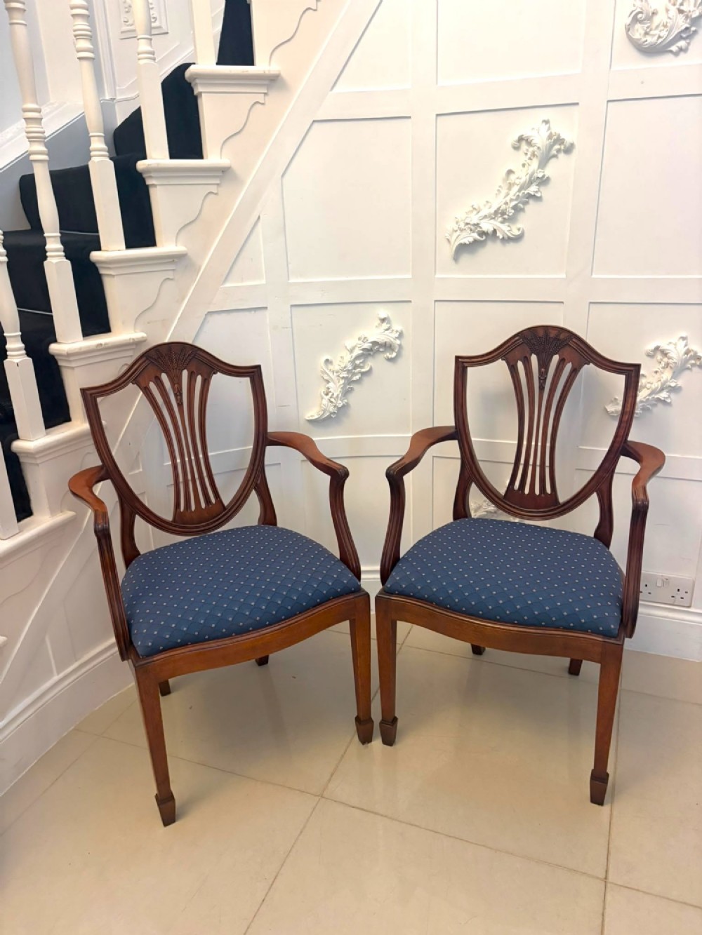 A set of twelve mahogany shield back dining chairs featuring carved backrest splats, square tapered legs, and blue patterned upholstered seats. View VII